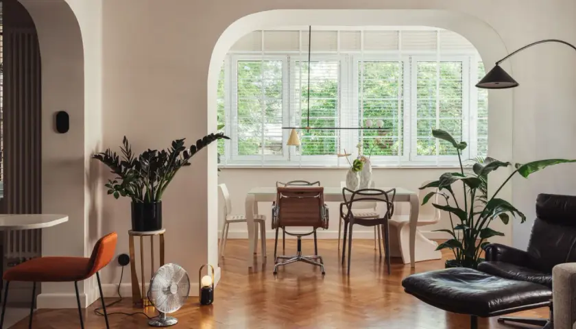 Eklektyzm w salonie: designerskie krzesła, rośliny i retro wentylator tworzą unikalną przestrzeń.
