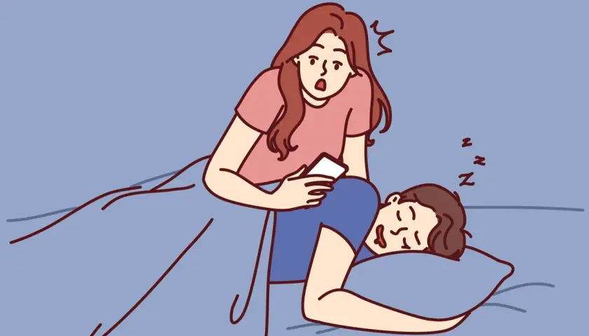 Donna sorpresa guarda il telefono mentre il partner dorme. Come gestire la gelosia in modo sano.