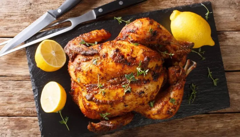 Pollo asado al horno, dorado y jugoso, con limones y hierbas frescas. ¡Listo para servir!