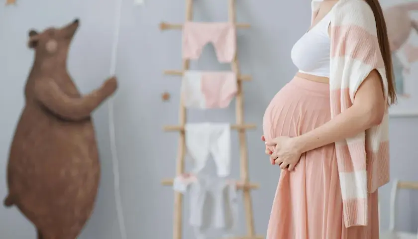 Ciężarna kobieta w pokoju dziecięcym, przygotowująca się na przyjście malucha. Czy można eksmitować kobietę w ciąży? To pytanie budzi wiele wątpliwości.