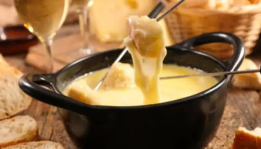 Une délicieuse fondue au beaufort, avec du pain croustillant et un verre de vin blanc.