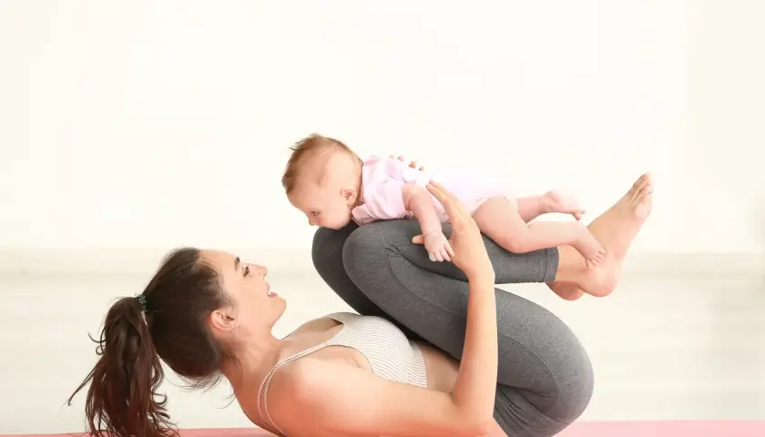 Mama ćwiczy z dzieckiem na macie. Połóg po cesarce to czas na delikatne ćwiczenia i budowanie więzi.
