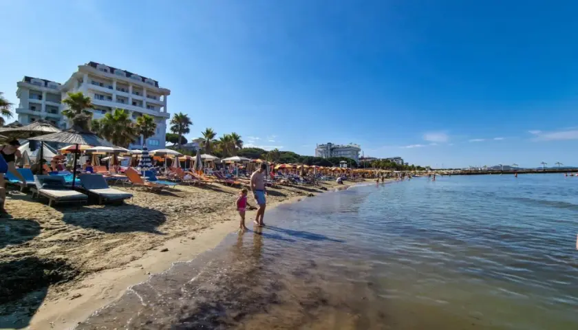 Słoneczna plaża w Golem, Albania, z leżakami, parasolami i hotelami. Idealne miejsce na wakacje, jedna z głównych atrakcji.
