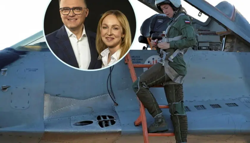 Urszula Brzezińska Hołownia w kombinezonie pilota obok myśliwca. W tle uśmiechnięci Szymon Hołownia i jego żona.