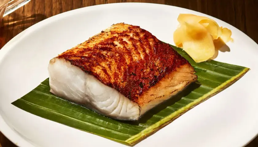 A perfectly seared Nobu miso black cod recipe, served on a banana leaf with pickled ginger.