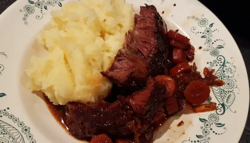 Un plat réconfortant de joue de bœuf à la bière, tendre et savoureuse, accompagnée d'une purée de pommes de terre onctueuse.