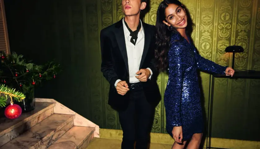 Un couple élégant, quelle tenue pour le réveillon du 31 ? Lui en smoking noir, elle dans une robe bleue à paillettes.