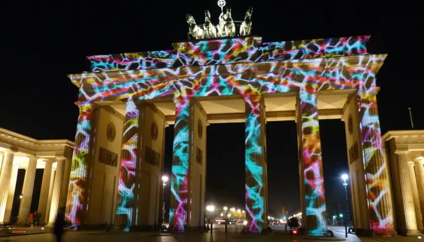 Brama Brandenburska nocą, oświetlona kolorowymi projekcjami. Ciekawostki o tym zabytku można odkrywać podczas takich widowisk.