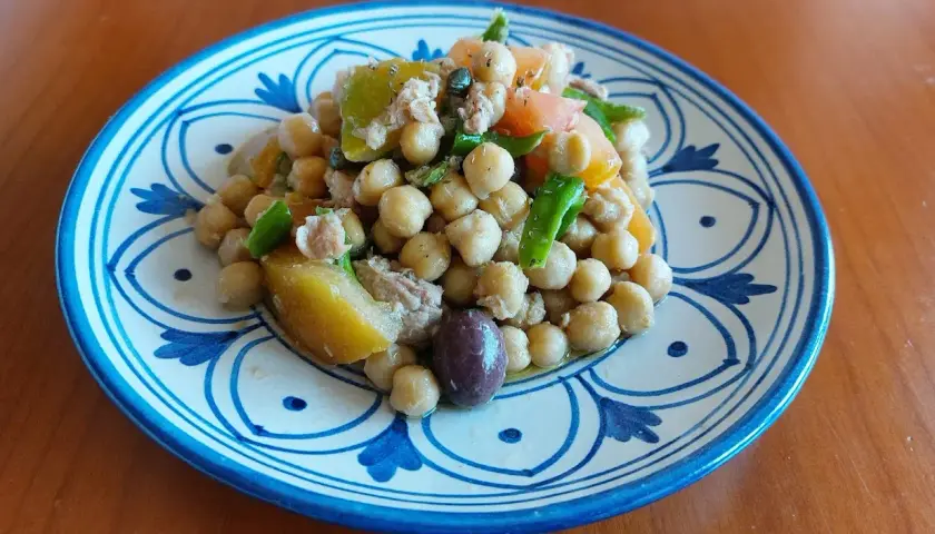 Un'appetitosa insalata di ceci alla siciliana, con pomodoro, olive e verdure fresche, servita su un piatto decorato.