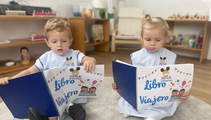 Niños leyendo un libro viajero infantil, con dibujos de cohetes y globos aerostáticos.
