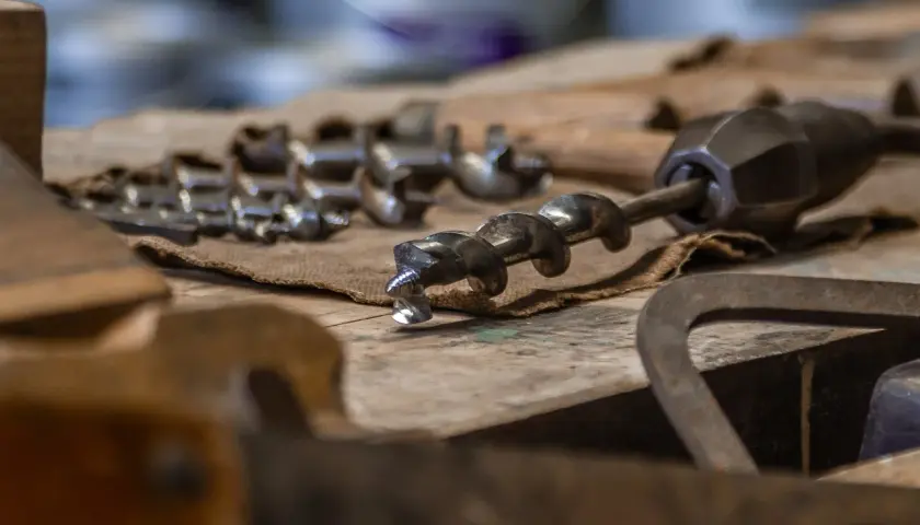 Utensili da falegnameria, tra cui punte elicoidali, per imparare come bucare il legno senza trapano.