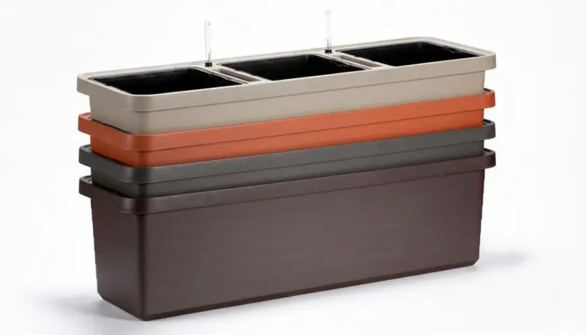 En stapel med fyra odlingslådor i plast i olika färger: ljusbeige, orange, grå och mörkbrun. De översta har vattenmätare.