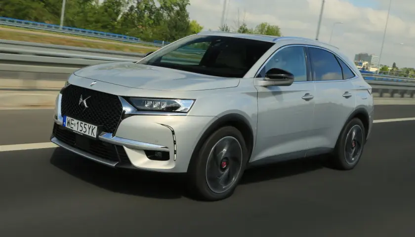 Srebrny DS 7 Crossback E-Tense pędzi autostradą, jego elegancka linia podkreślona przez dynamiczne światła.