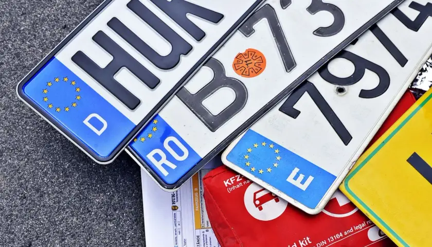Kilka tablic rejestracyjnych z różnych krajów UE, dokumenty i apteczka. GKW rejestracja w tle.