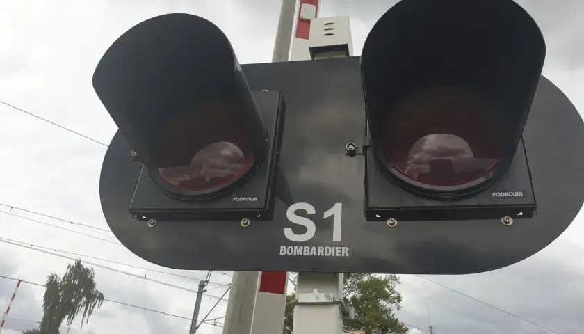 Dwa czerwone światła na przejeździe kolejowym Bombardier S1, gotowe do zatrzymania ruchu.