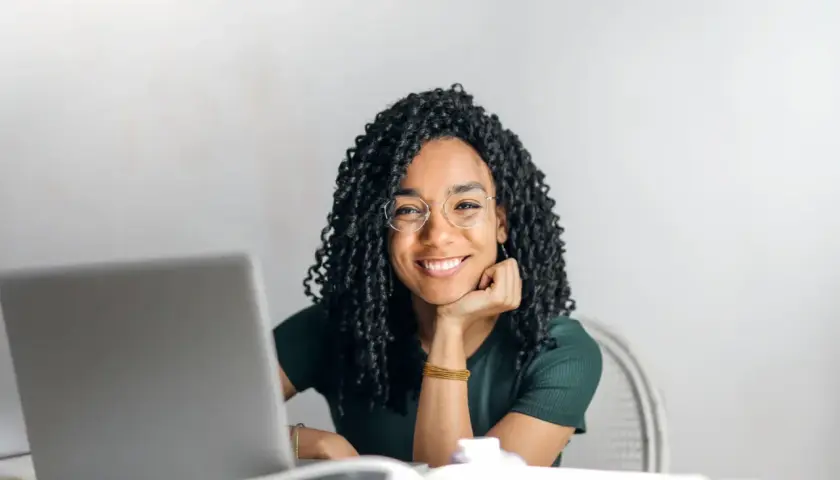 Donna sorridente con occhiali, laptop e libri. Si chiede dopo quante sedute di psicoterapia si vedono i risultati.