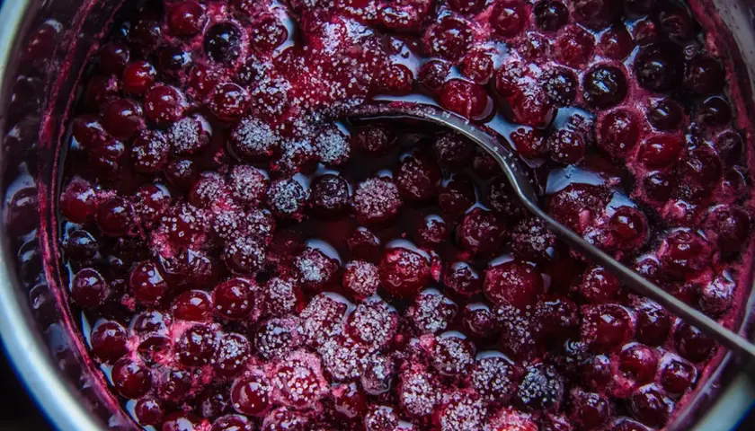 Gotowy do słoików dżem z wiśni z żelfixem, błyszczący od cukru i gotowy do degustacji.