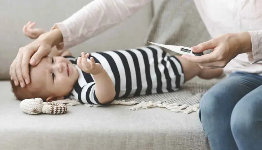 Mamma controlla la febbre al neonato di 1 mese con un termometro. 38.0°C.