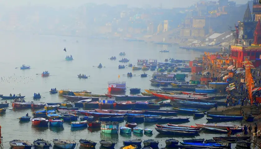 Łodzie na rzece Ganges, w tle mgliste miasto i świątynie.