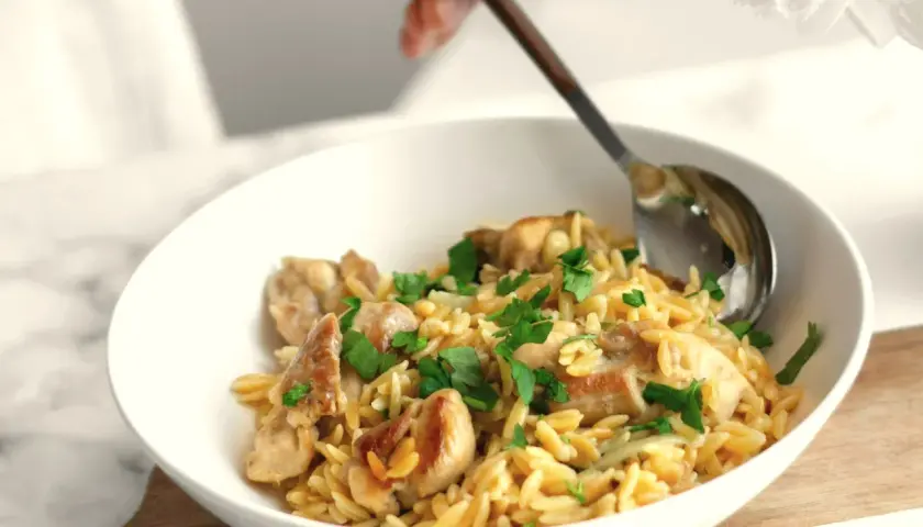 Miseczka z kurczakiem i makaronem orzo, posypana natką pietruszki. Idealne na proste przepisy na obiad.