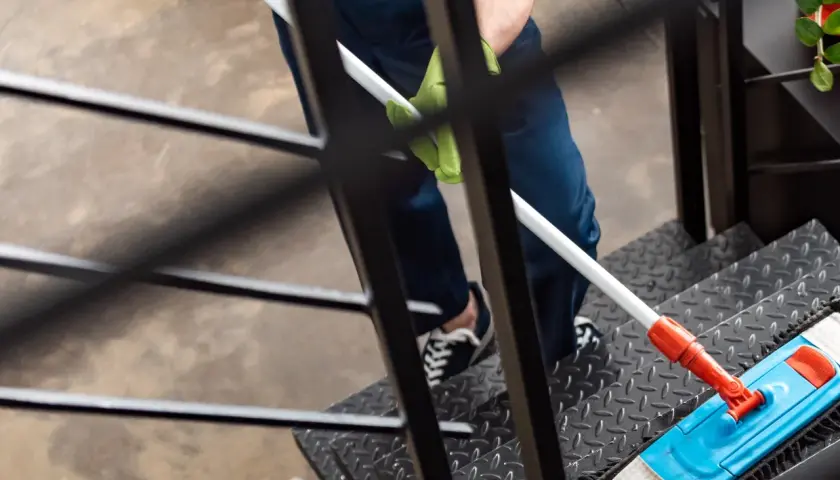 Person reinigt Treppe mit Mopp. Dies kann durch den **Entlastungsbetrag Haushaltshilfe** finanziert werden.