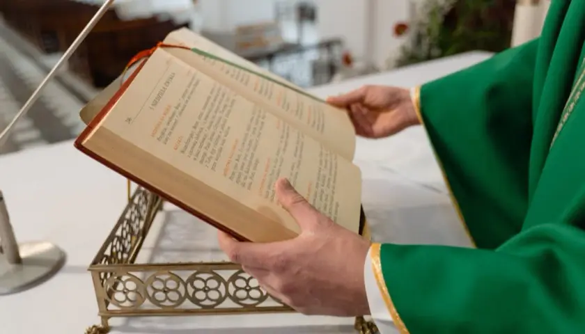 Kapłan w zielonej szacie czyta z księgi liturgicznej. Zastanawiasz się, ile trwa msza niedzielna?