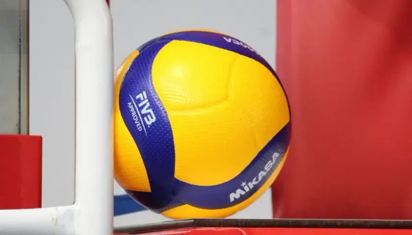 Żółto-niebieska piłka Mikasa V300, zatwierdzona przez FIVB, gotowa do gry na boisku.