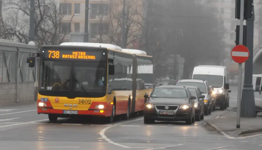 Autobus linii 738 z napisem "METRO RATUSZ ARSENAŁ" w ruchu miejskim, w tle samochody i budynki.