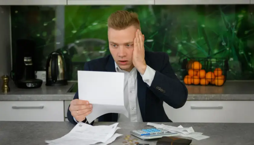 Zmartwiony mężczyzna z dokumentami i kalkulatorem. Czy umowa zlecenie chroni przed komornikiem?