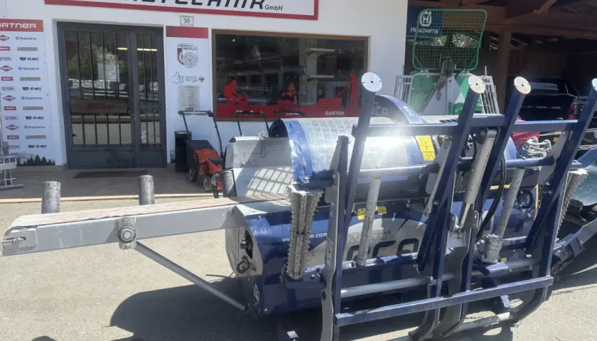 Blauer Holzspalter Tajfun RCA 400 gebraucht vor einem Landtechnikgeschäft.