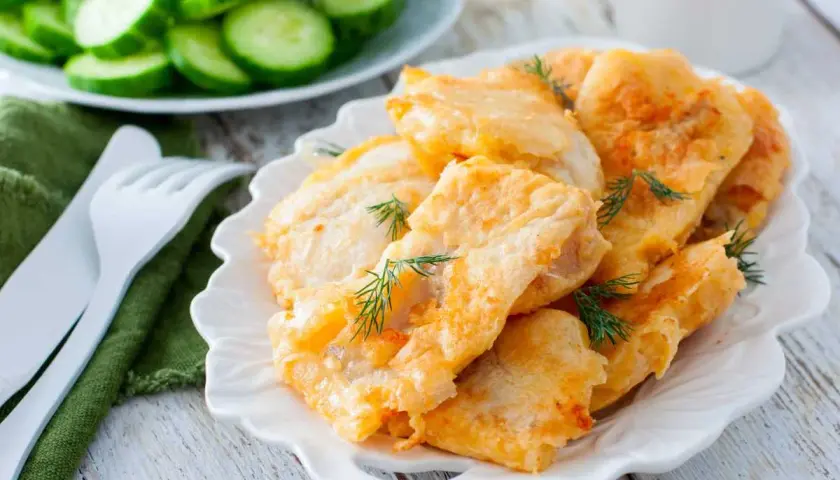 Deliciosa merluza rebozada, crujiente por fuera y tierna por dentro, adornada con eneldo fresco. Acompañada de rodajas de pepino.