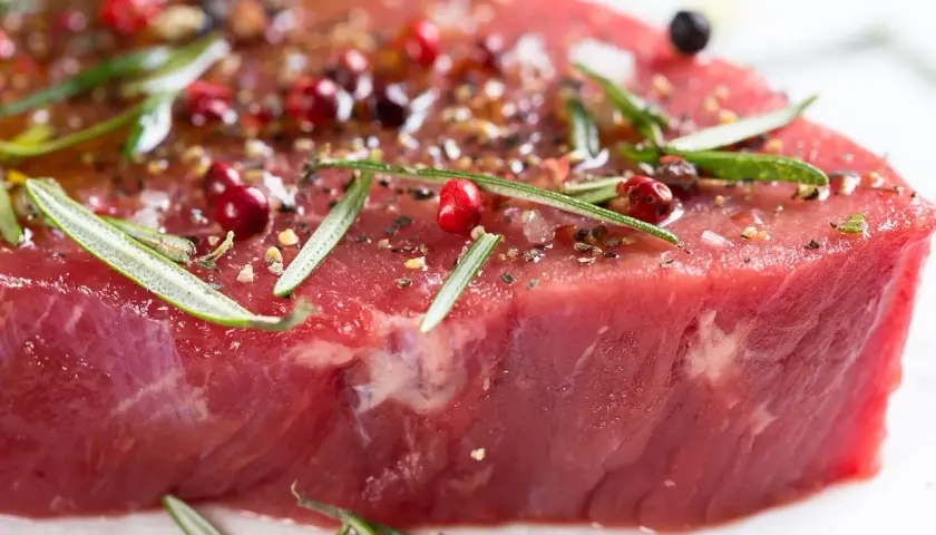 Un morceau de viande rouge, assaisonné de poivre rose, de romarin et d'épices, prêt à devenir l'une des 10 meilleurs viandes du monde.