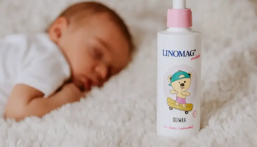 Śpiące dziecko obok butelki oliwki dla noworodka Linomag.