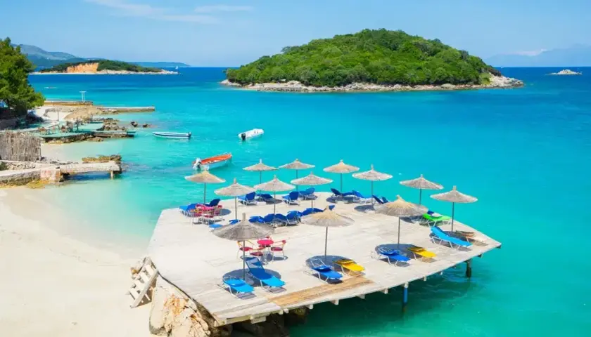 Albania, jakie morze? Turkusowe wody, piaszczysta plaża, leżaki i parasole na drewnianym pomoście. Idealne miejsce na wakacje.