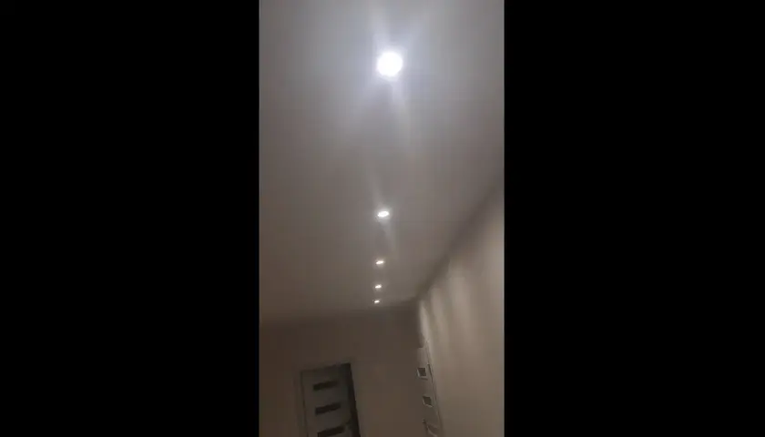W korytarzu widać rząd wbudowanych w sufit lamp, które tworzą migające światło.