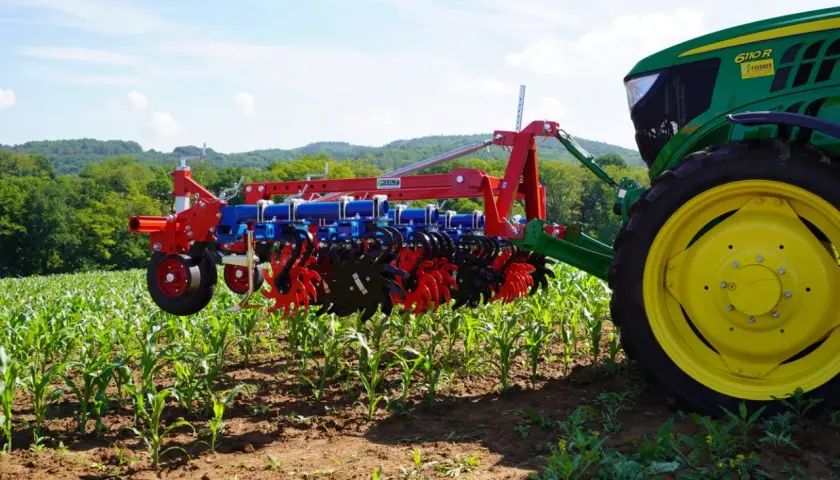 Moderner Grubber für die Landwirtschaft im Einsatz, der den Boden zwischen jungen Maispflanzen lockert.