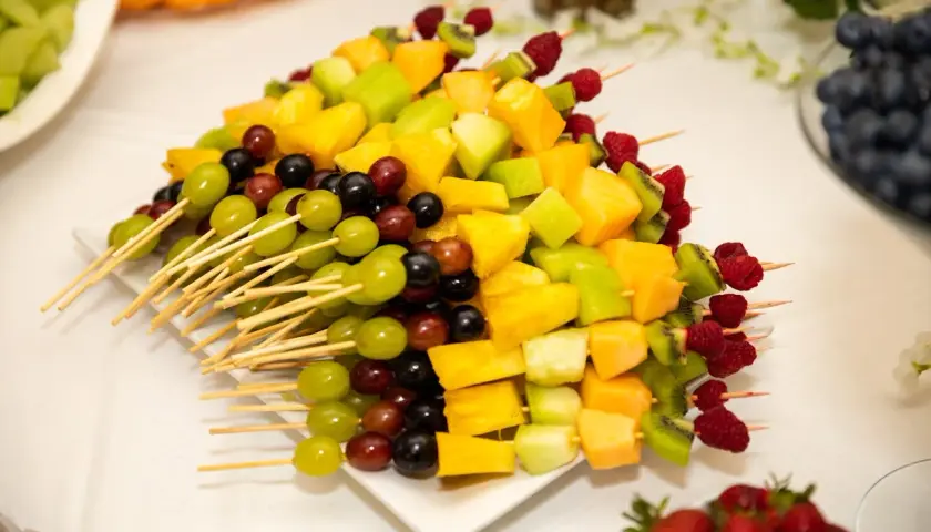 Kolorowa deska owoców na imprezę: szaszłyki z winogron, melona, kiwi, ananasa i malin.