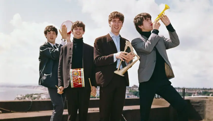 The Beatles w swoich eleganckich garniturach, grając na instrumentach, tworzą niepowtarzalne The Beatles utwory.