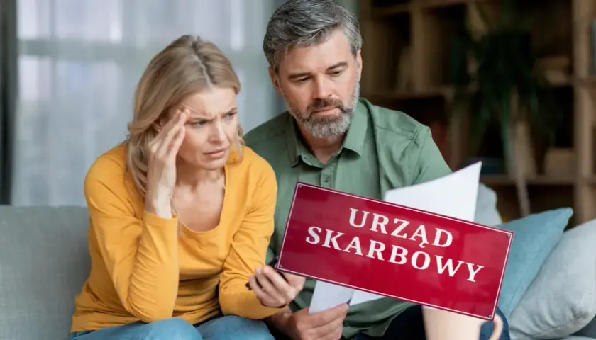 Para martwi się o pieniądze z wesela na konto. Na stole leży tabliczka "Urząd Skarbowy", a kobieta trzyma się za głowę.