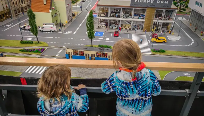 Dwie dziewczynki podziwiają miniaturowe miasto, gdzie znajdują się sky tower atrakcje dla dzieci.