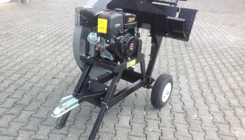 Robuste wippsäge mit benzinmotor, bereit für den Einsatz im Garten oder Wald. Mit Anhängerkupplung und Rädern für einfachen Transport.