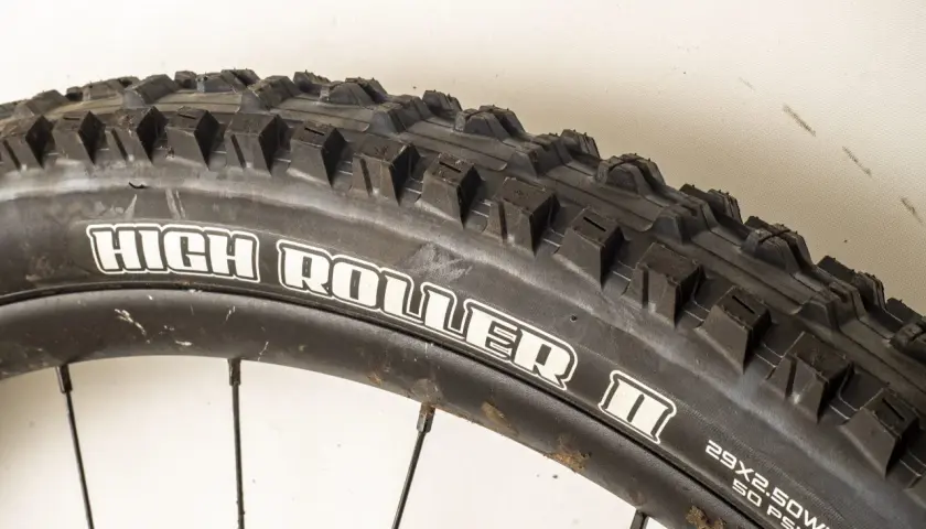 Close-up of a Maxxis High Roller II tire, ready for a review. Its aggressive tread promises excellent grip on challenging trails.