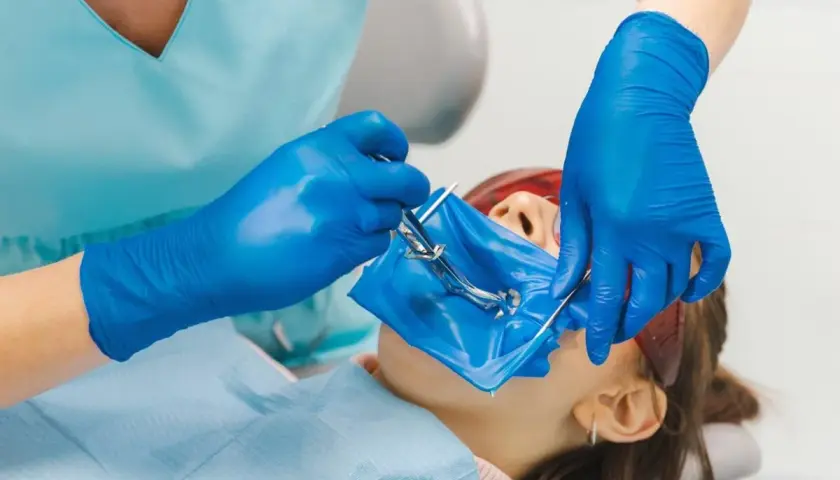 Dentysta zakłada koferdam, izolując pole zabiegowe.