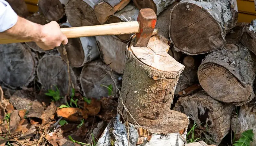 Mann spaltet Holz mit Axt. Der Stapel zeigt, wie man Holz stapeln kann, mit Rinde nach oben oder unten.