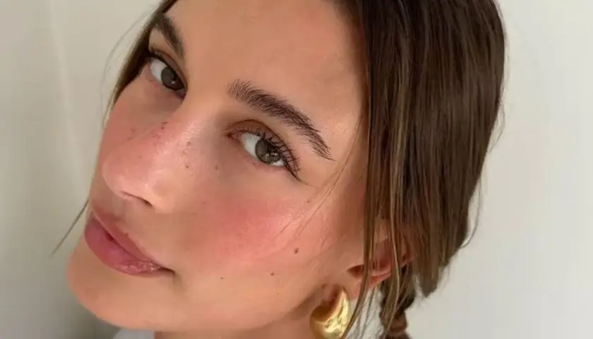 En närbild på en kvinna som har valt att applicera rouge för en naturlig, rosig look.