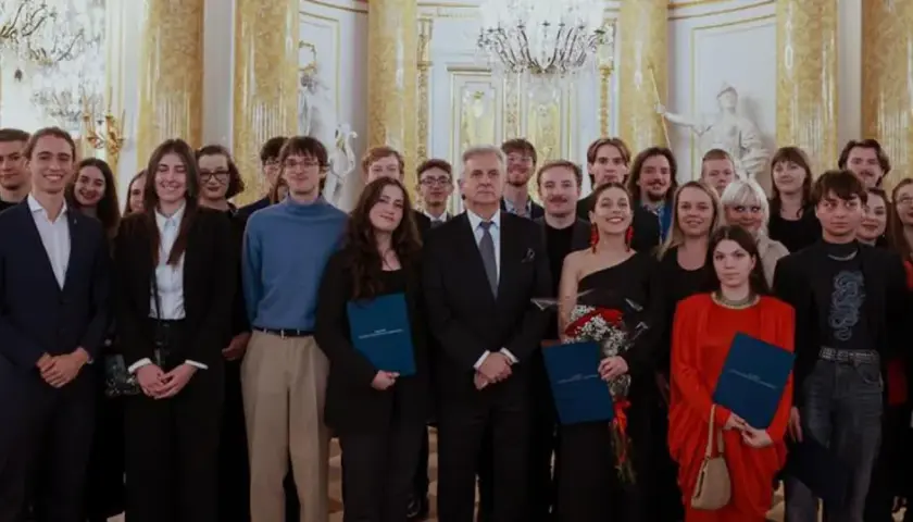 Grupa młodych ludzi w eleganckich strojach odbiera stypendium artystyczne ministra kultury.