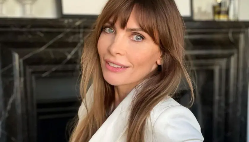 Agnieszka Dygant w białej marynarce, z burzą brązowych włosów i niebieskimi oczami.