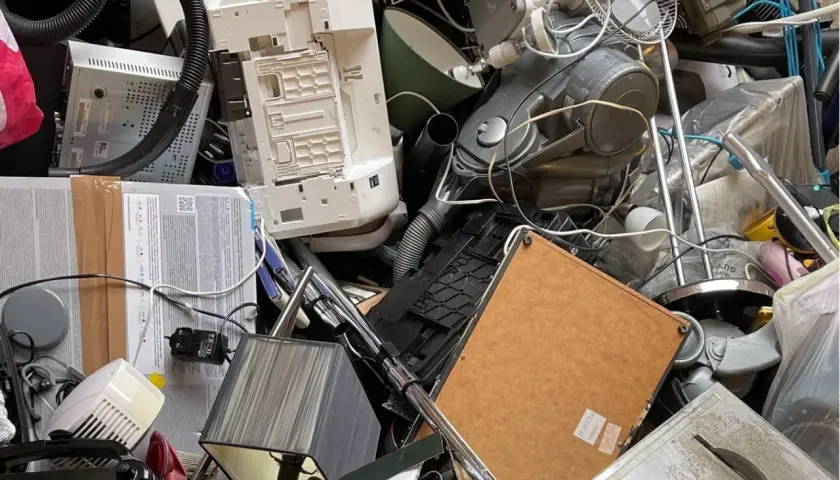 Stos starych urządzeń elektronicznych: drukarka, odkurzacz, wentylator, lampa.