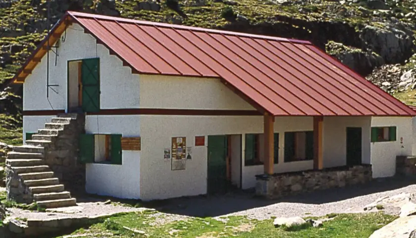 Un refugio de montaña en Cataluña, con tejado rojo y escaleras de piedra.