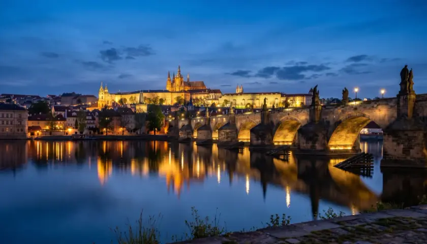 Idealny pomysł na praga na weekend: nocny widok na Most Karola i Zamek Praski, z odbiciem świateł w Wełtawie.